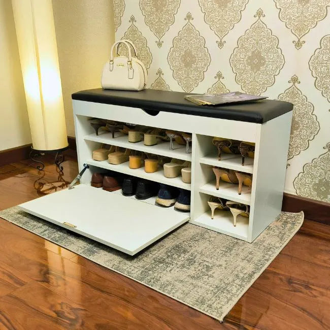 White shoe rack organizer with bench with black cushioned top in a room with patterned wallpaper.