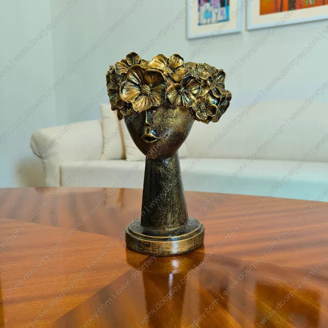 Decorative decor bronze sculpture of a head with floral crown on a wooden table