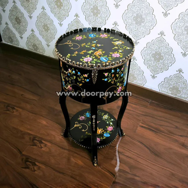Decorative round wooden table with hand painted patterns on a wooden floor.