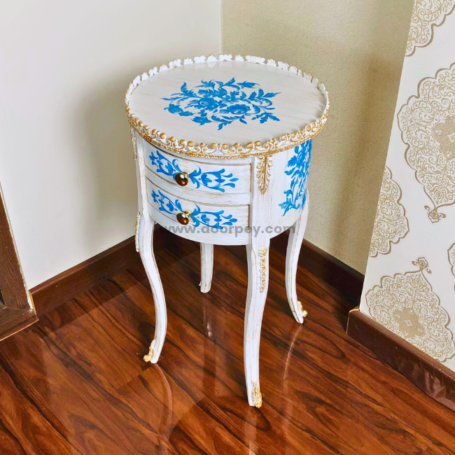 A round wooden table with blue floral patterns and gold trimmings, featuring metal hardware and standing on curved legs.