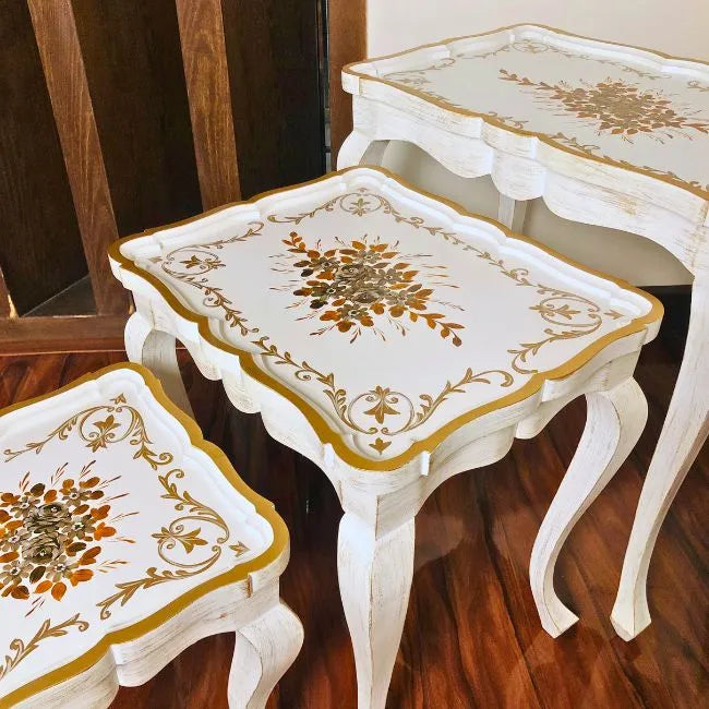 Space-saving Fern Harmony wooden nesting tables stacked neatly, featuring a white and gold hand-painted design