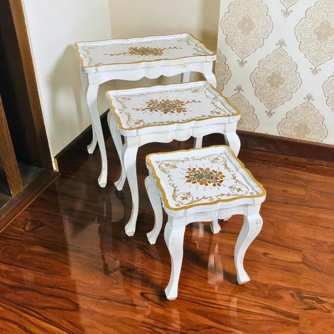 Close-up of Fern Harmony nesting tables, highlighting the fine hand-painted gold floral patterns on a white wooden surface