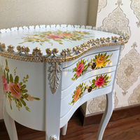 Closeup of a hand painted wooden table with flowing floral design and golden trims.