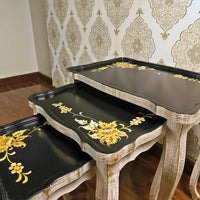 Side view of Golden Fern wooden nesting tables showcasing intricate gold floral detailing on a black and distressed white wood finish