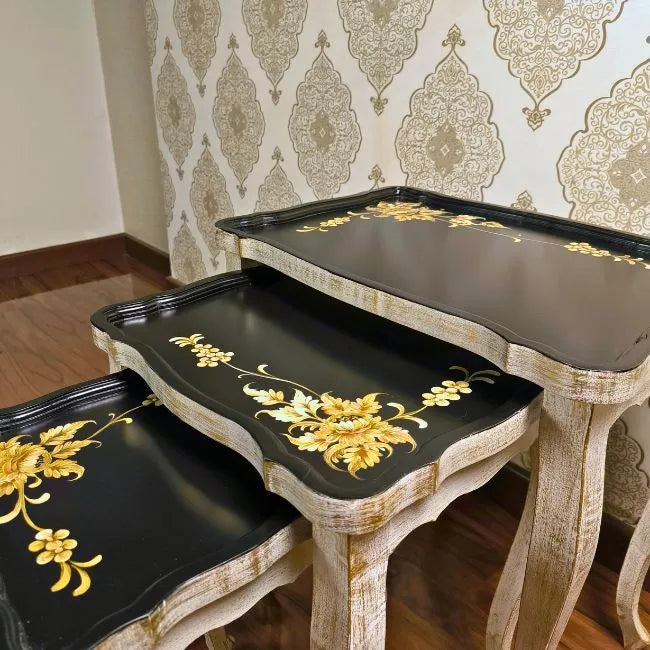 Side view of Golden Fern wooden nesting tables showcasing intricate gold floral detailing on a black and distressed white wood finish