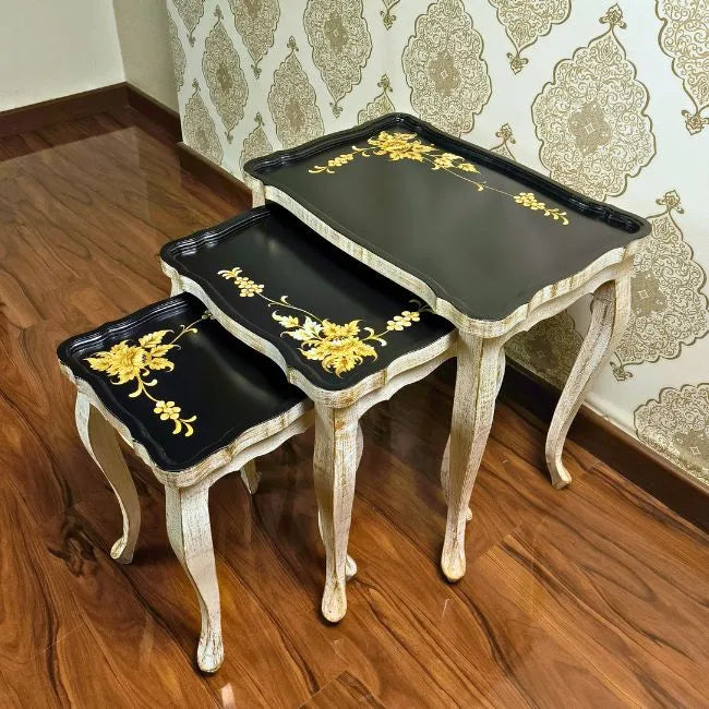Close-up of Golden Fern nesting tables, highlighting the fine gold floral hand-painted designs on a black wooden surface
