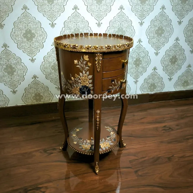 Decorative wooden side table with gold embellishments against a patterned wallpaper background