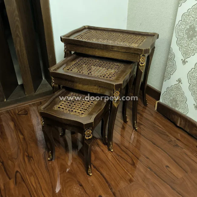 Set of three wooden nesting tables with lattice design on a wooden floor.