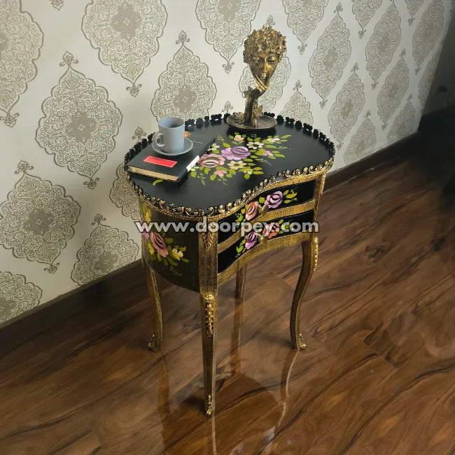 Decorative wooden side table with floral patterns and gold accents against a patterned wall.