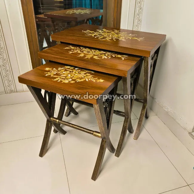 Set of three wooden nesting tables with decorative elements on a tiled floor.