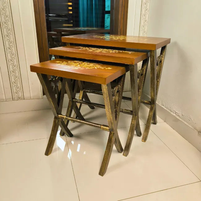 Side view of Rustic Harmony wooden nesting tables showcasing intricate floral artwork and sturdy wooden legs with a rustic finish