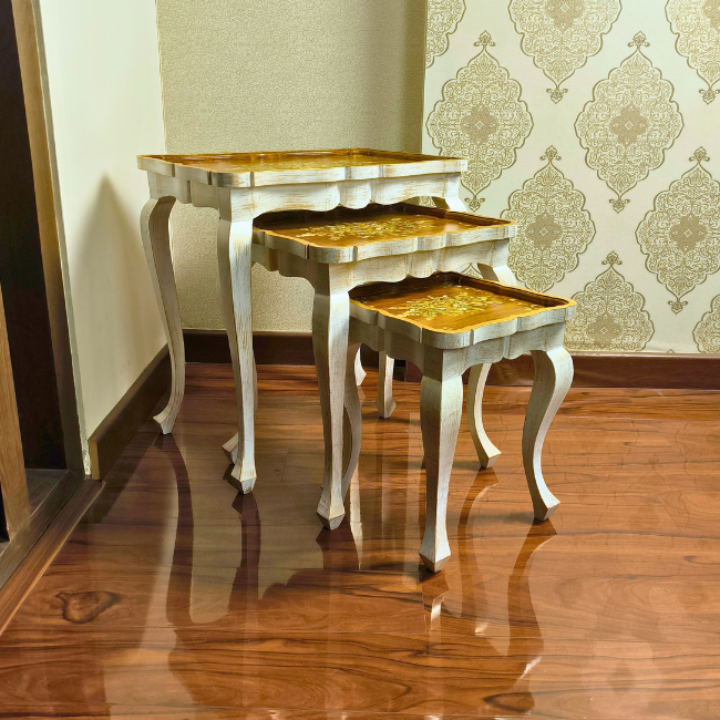 Space-saving Rustic Ramble nesting tables stacked together, featuring hand-painted gold floral designs on a natural wood finish.