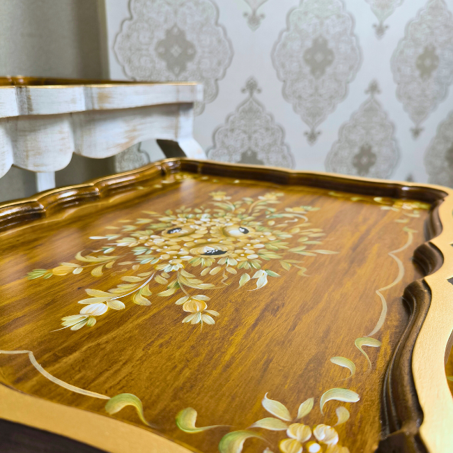 Close-up of Rustic Ramble nesting tables, highlighting the fine gold floral hand-painted designs on a smooth wooden surface.