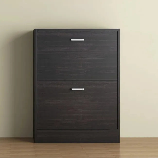 Dark wood shoe cabinet with two drawers against a beige wall.