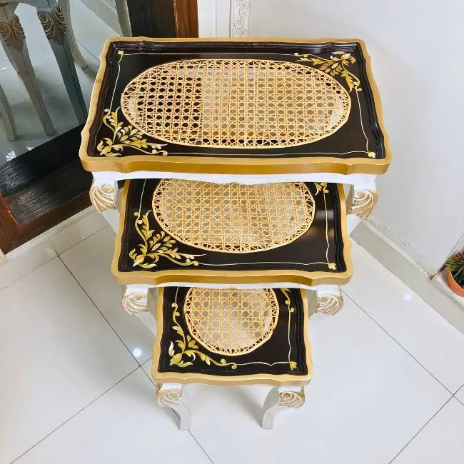 Close-up of black and gold nesting table’s cane top, showcasing fine craftsmanship and elegant gold-painted accents