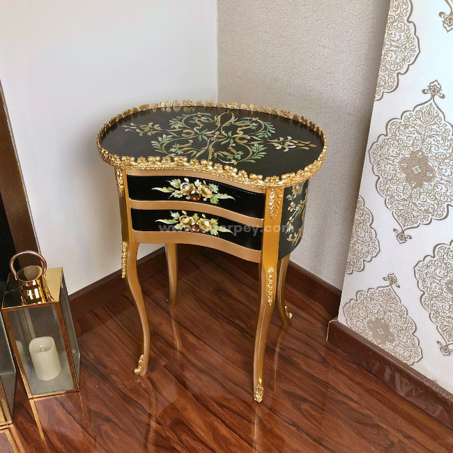 A black and golden decorative wooden side table on a wooden floor.