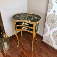 A black and golden decorative wooden side table on a wooden floor.