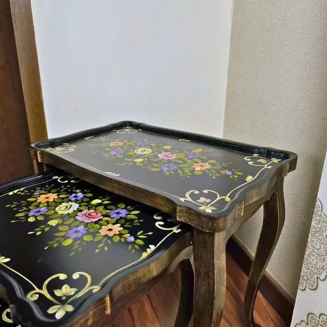 Side view of Blossom Breeze wooden nesting tables showcasing intricate multicolor floral artwork and a deep black finish with gold detailing