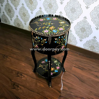 Decorative round wooden table with hand painted patterns on a wooden floor.