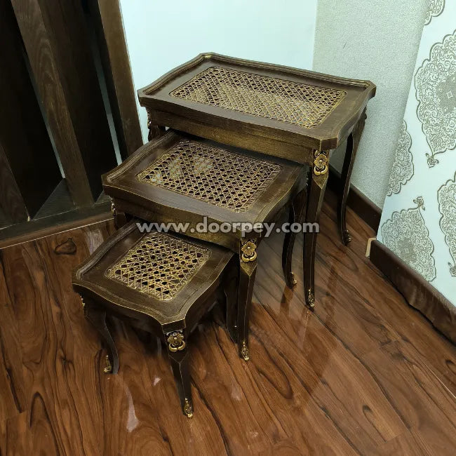 Set of three wooden nesting tables for living and dining room on a wooden floor.