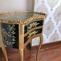 Close up shot of a black and golden decorative wooden end table on a wooden floor.