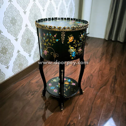 Decorative round wooden end table with hand painted floral patterns on a wooden floor.