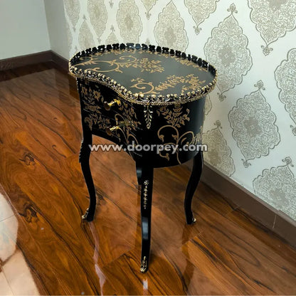 Decorative black wooden table with gold accents on a wooden floor.