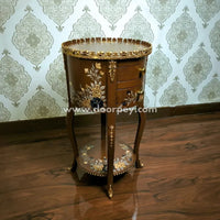 Decorative wooden side table with gold embellishments against a patterned wallpaper background