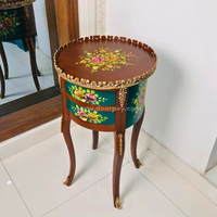 A decorative wooden side table in brown and deep green color with colorful painted patterns and golden trims.