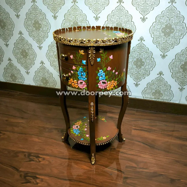 Decorative round wooden table with floral patterns against a patterned wallpaper background
