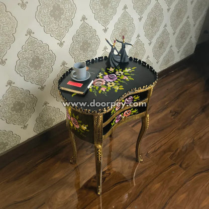 Decorative wooden bedside table with floral patterns and a couple figurine against a patterned wall.