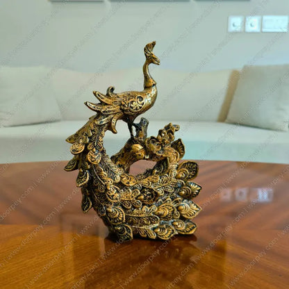 Decorative golden peacock sculpture on a wooden surface with a blurred background