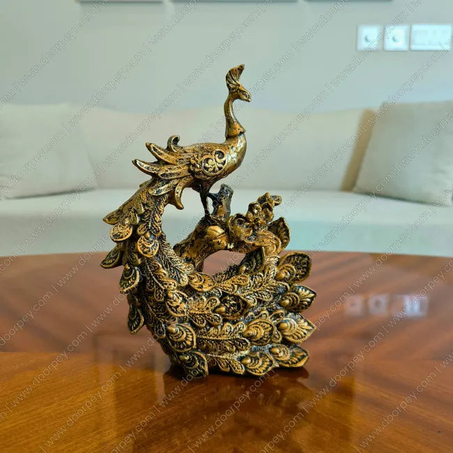 Decorative golden peacock sculpture on a wooden surface with a blurred background