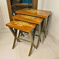 Space-saving Rustic Harmony nesting tables stacked together, featuring a warm woodgrain surface with gold floral detailing