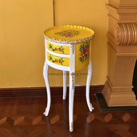 A white and yellow wooden side table with painted patterns on a wooden floor.