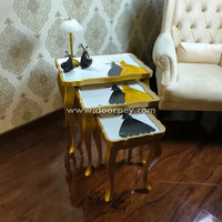 Wooden nest tables with decorative items against a patterned wall.