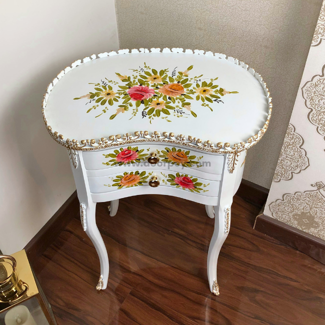 Elevated view of a white wooden table with handpainted patterns and gold trims.