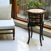 A picture of a wooden side table infront of a window and next to a chair