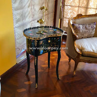 Decorative wooden side table with intricate designs next to a ornate chair in a room.