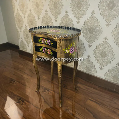 Decorative wooden side table with floral patterns against a patterned wallpaper background
