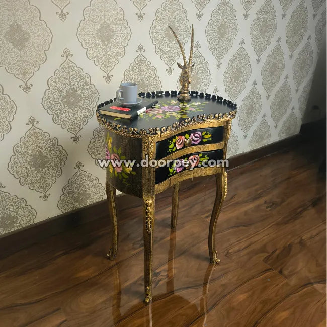 Decorative wooden table with floral designs against a patterned wallpaper background