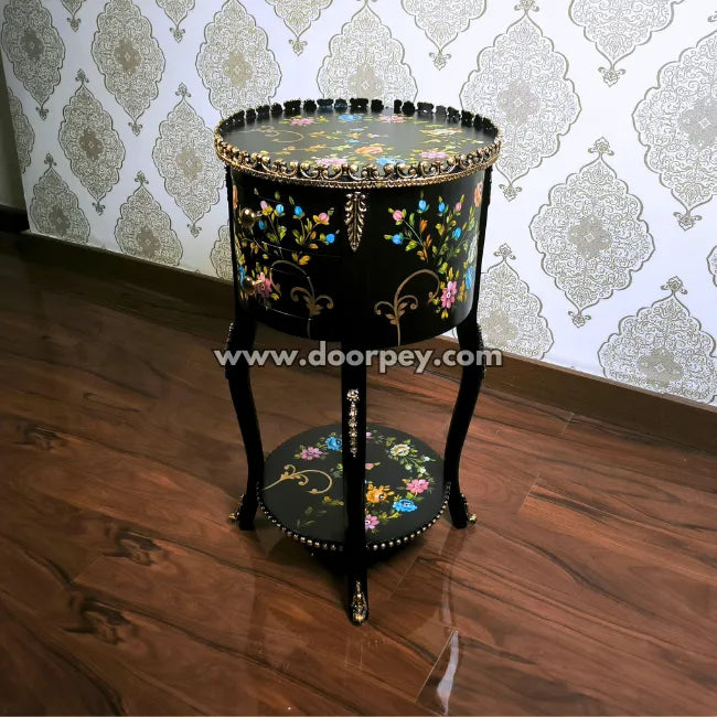 Decorative round wooden accent table with hand painted floral patterns viewed from a side angle