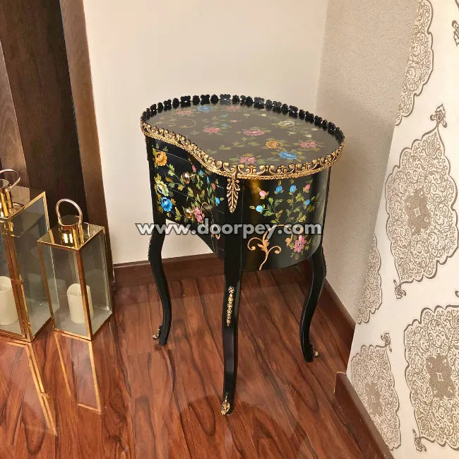Decorative wooden end table with floral patterns on a wooden floor.