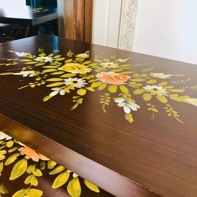 Close-up of Woodland Wonders nesting tables, highlighting the hand-painted floral artwork on a dark wooden surface.